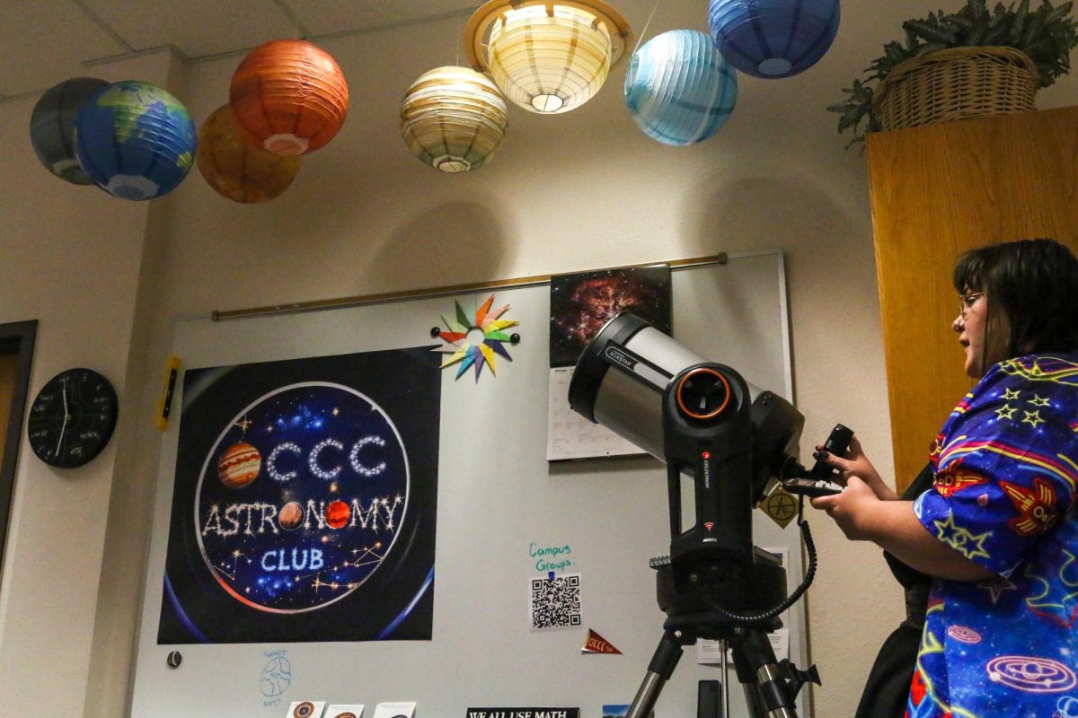 Bobie Johnson, president of the astronomy club, prepares her telescope by removing the lens cover and carefully positioning its direction with a remote.