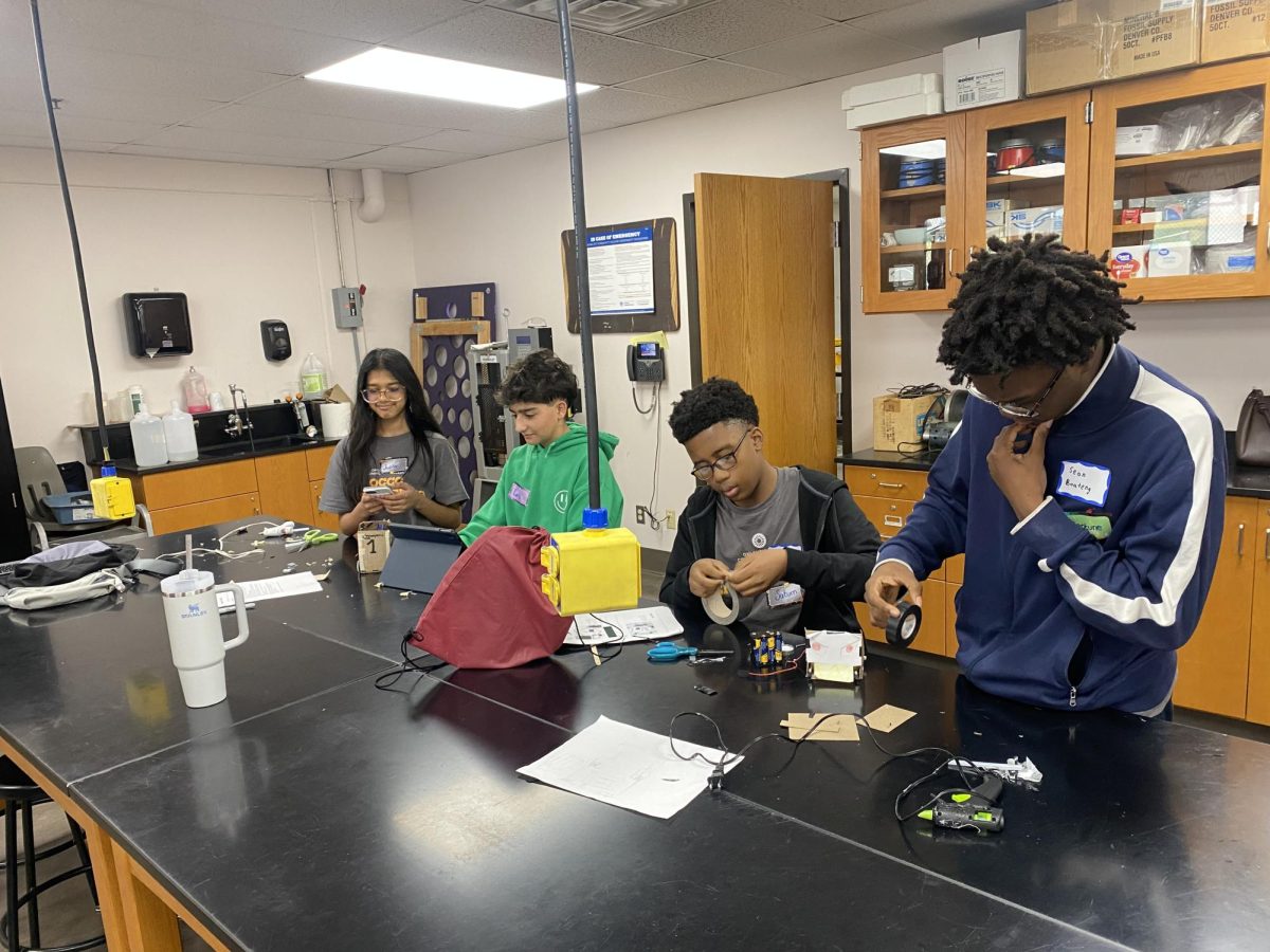 Students focus on the physical components of their projects, applying duct tape and securing battery packs to construct their non-programmable circuits.